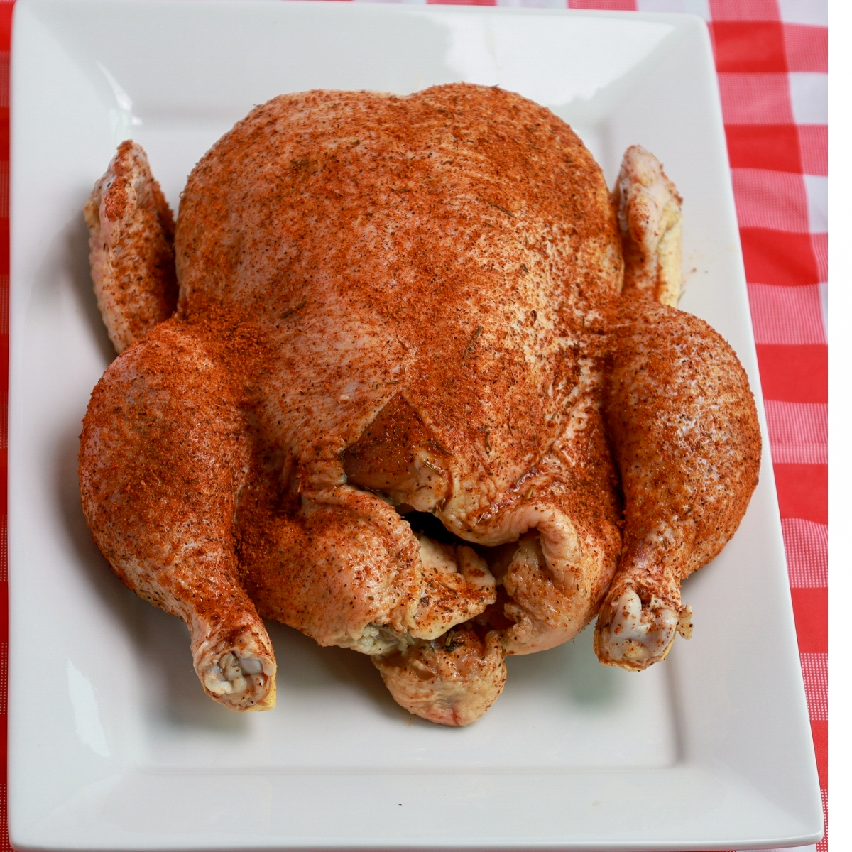 Whole chicken perfectly seasoned and prepared for smoking, with a flavorful rub.