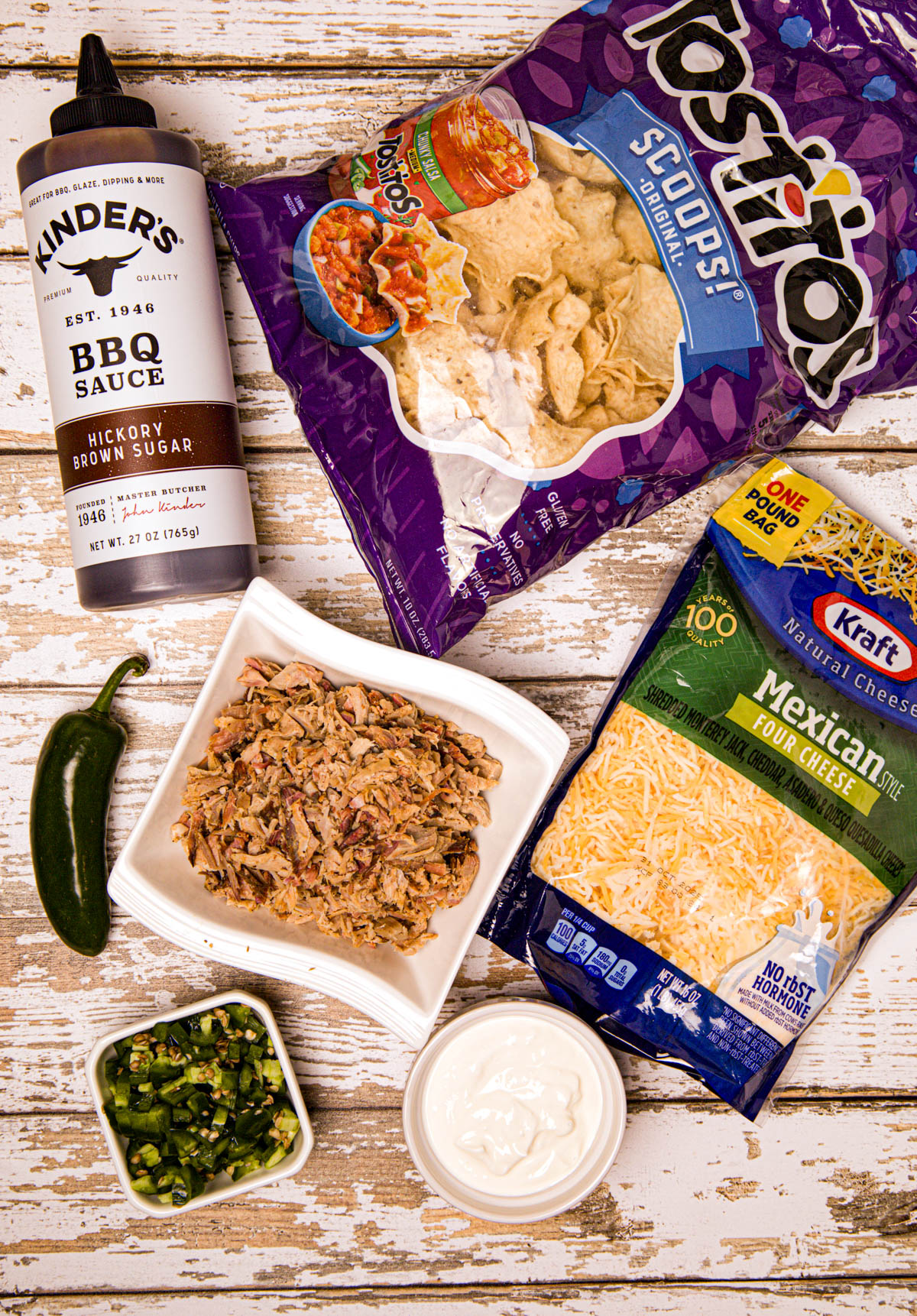 A top-down view of all ingredients: diced jalapeños, shredded cheese, sour cream, and smoked pork, all ready to be assembled.