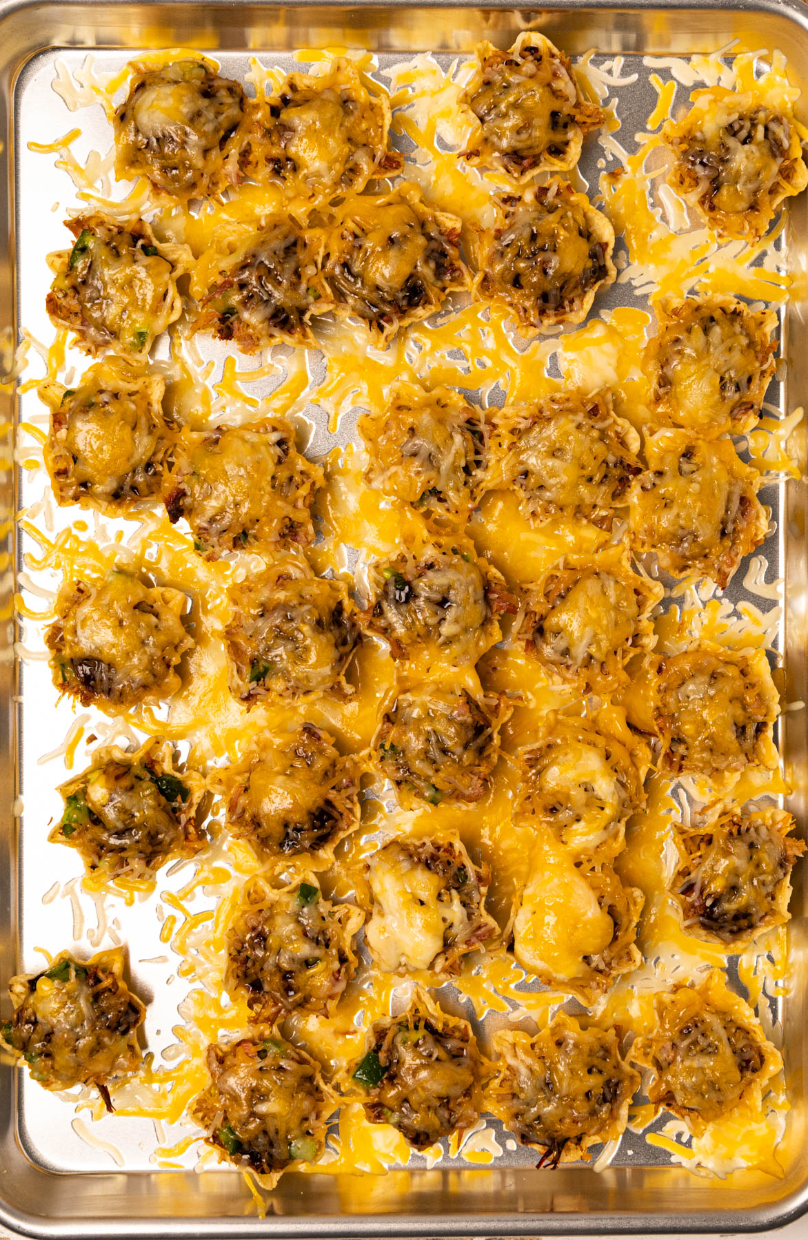 A fully baked pulled pork bite, topped with barbecue sauce, sitting on a crispy chip, ready to enjoy.