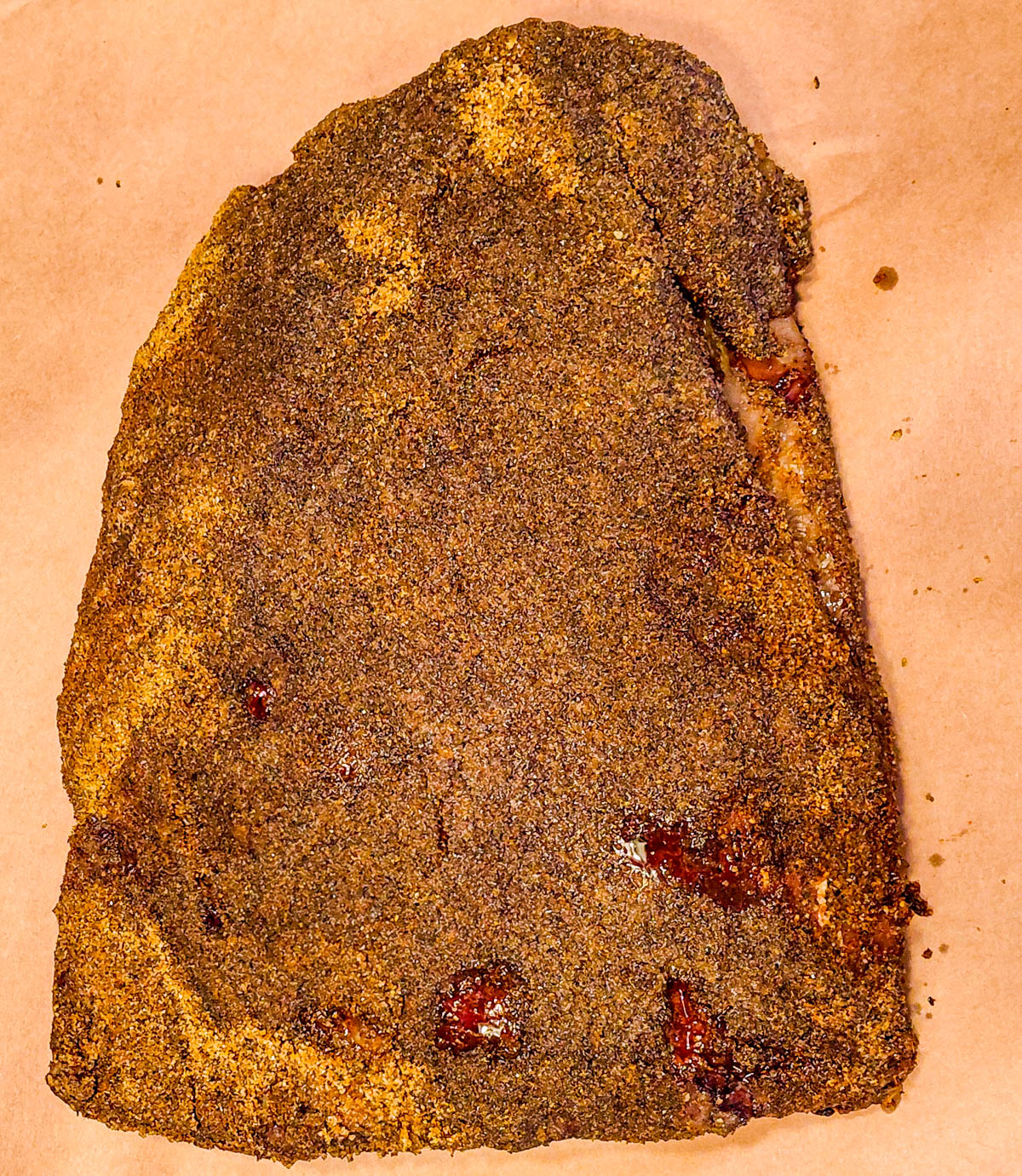 Seasoned beef dino ribs resting on butcher paper, ready to be wrapped and returned to the smoker for the final stage.