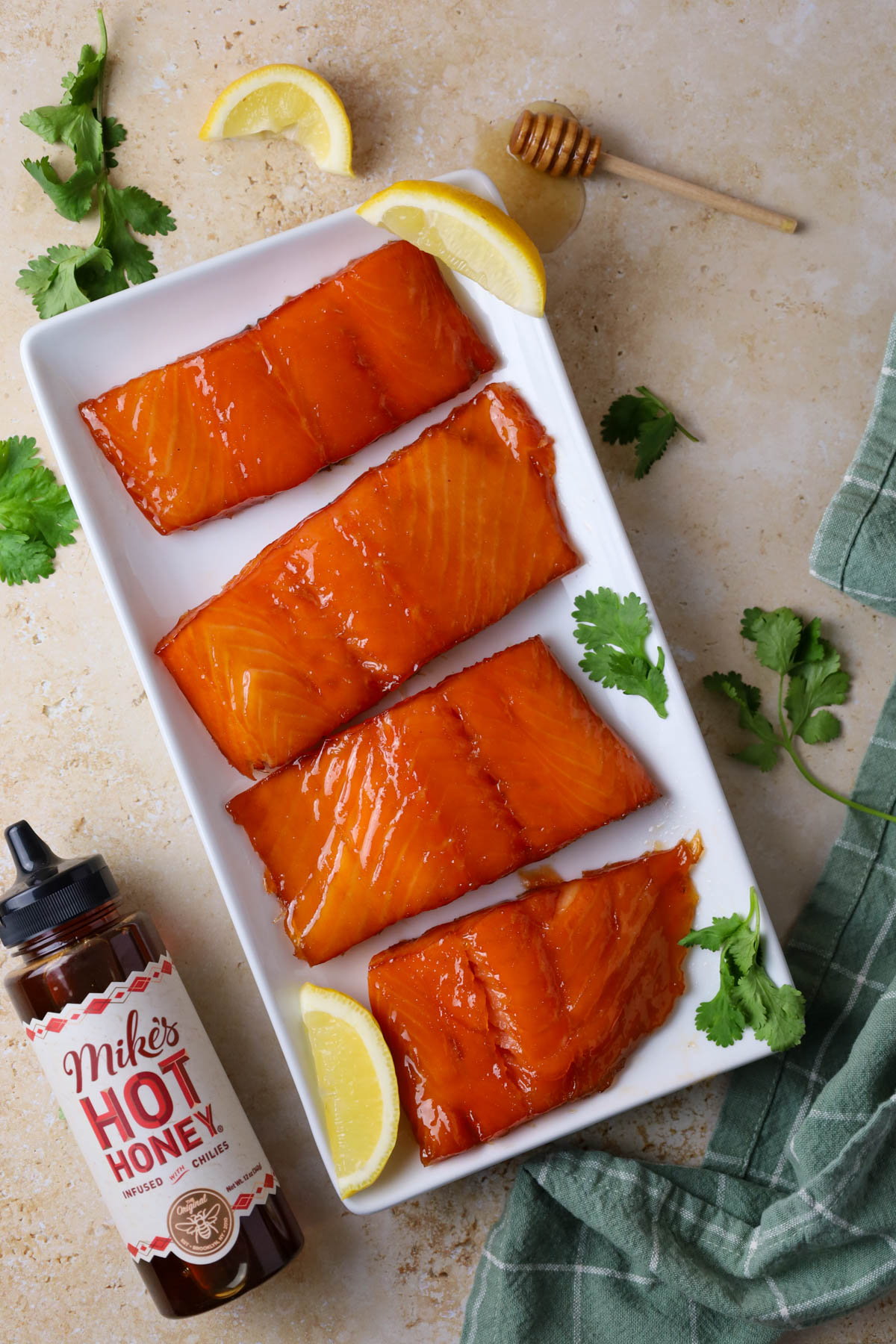 A beautifully smoked salmon fillet with a glossy, golden crust, garnished with fresh herbs and lemon wedges.