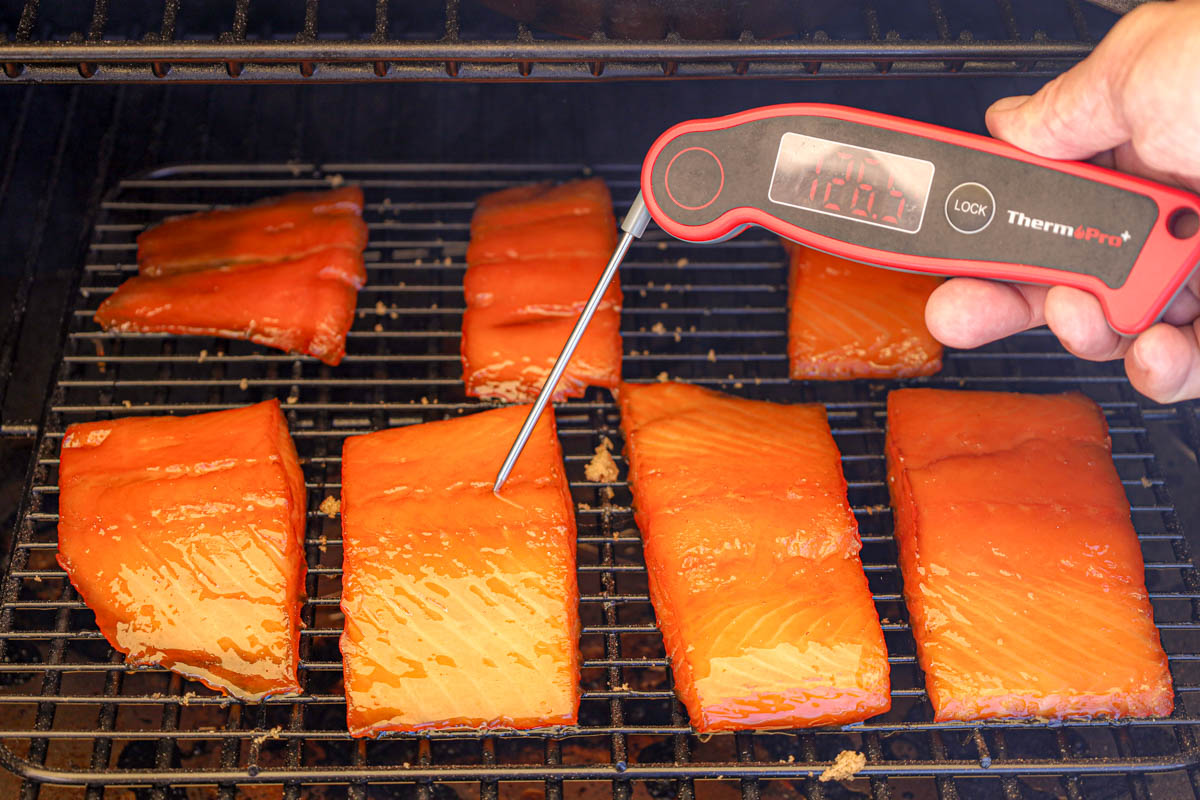 Probe the thermometer inside the salmon fillet to check its internal temperature.
