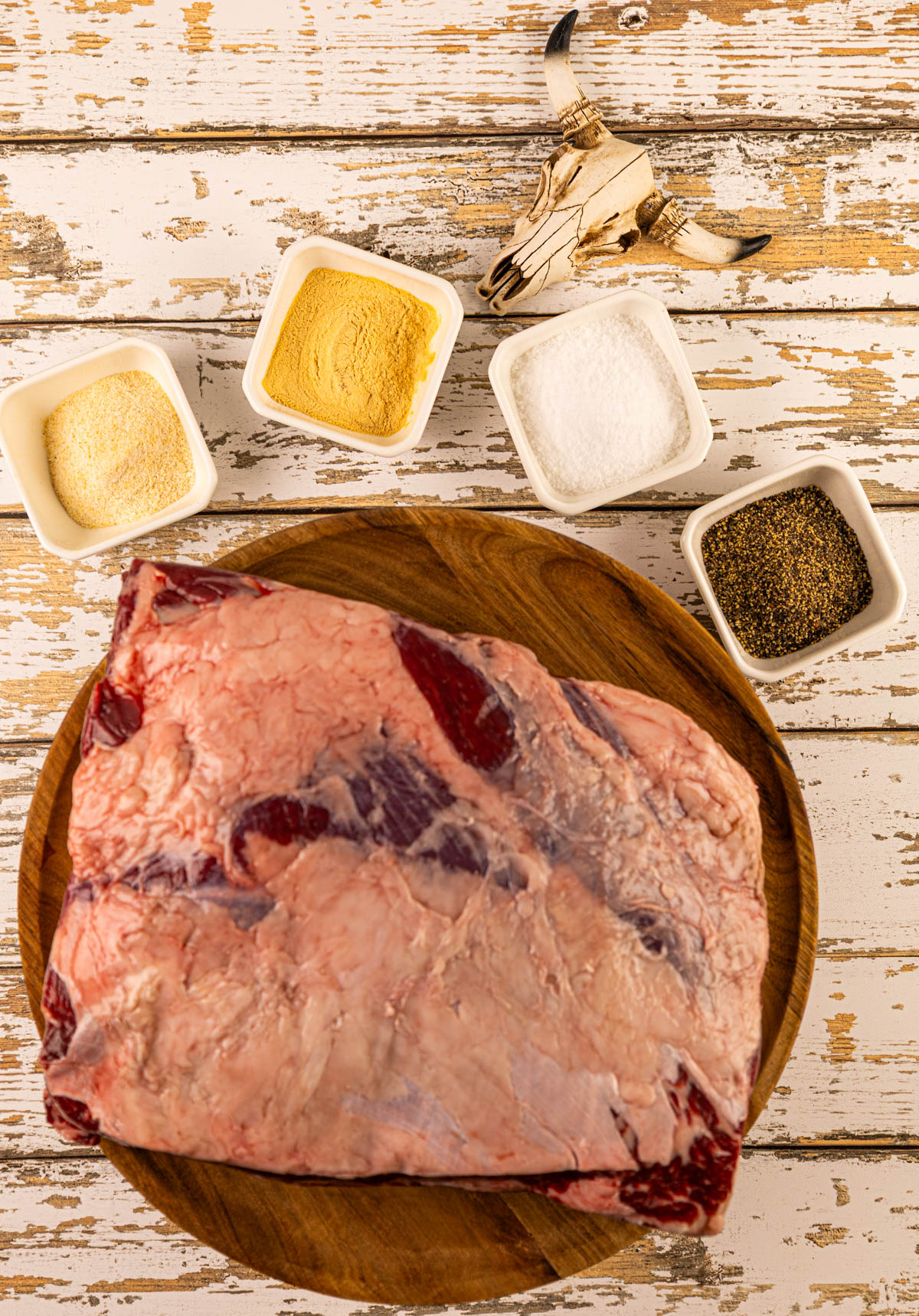 Raw beef dino ribs with a layer of fat, with seasonings, ready to be prepared for the smoker.