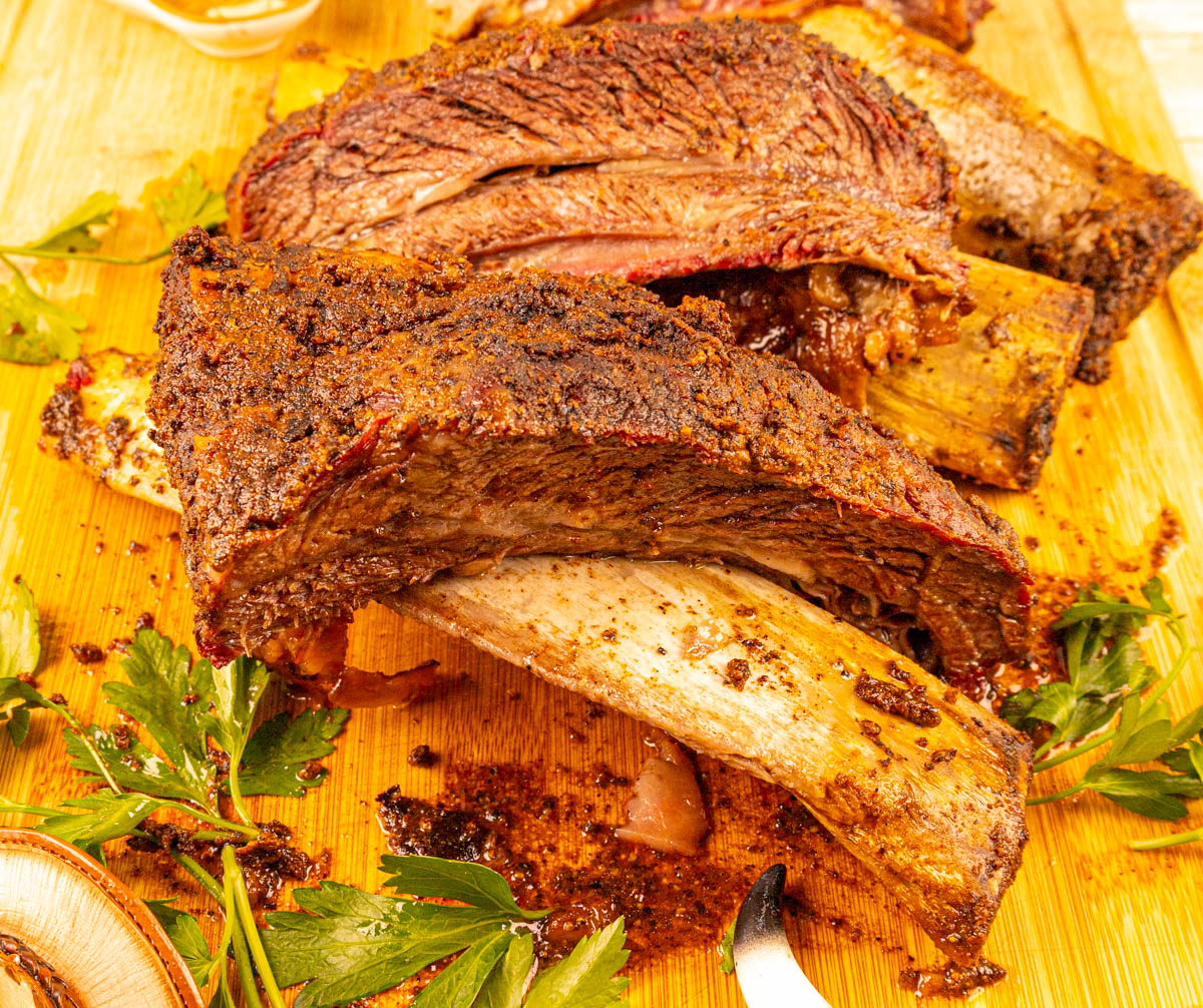 Beef dino ribs on a cutting board, with the bones starting to fall out, tender and ready to be served.